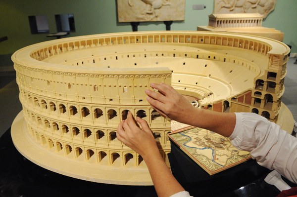 Manos tocando la maqueta del Coliseo.
