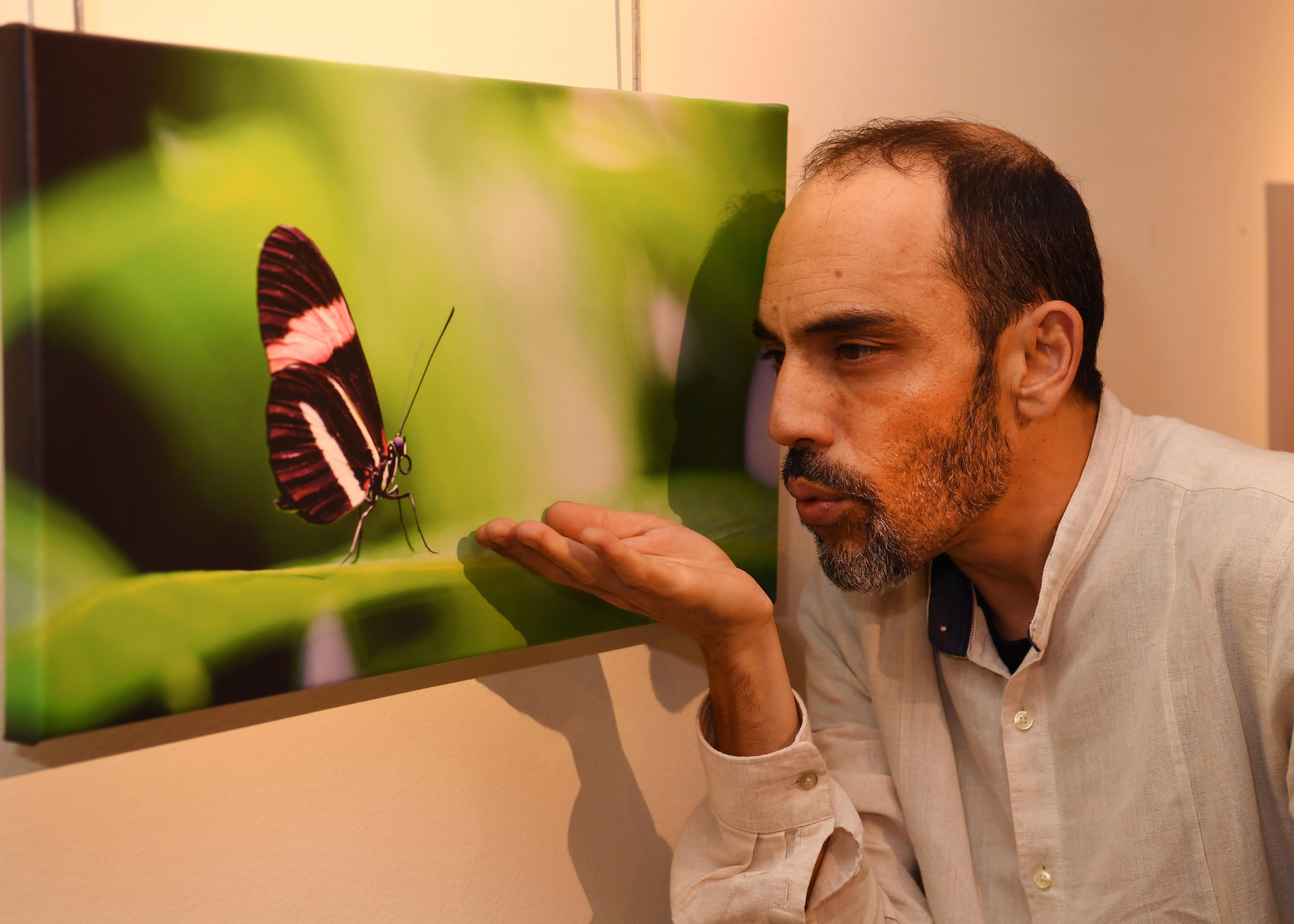 El fotógrafo junto a una de sus obras donde aparece una mariposa