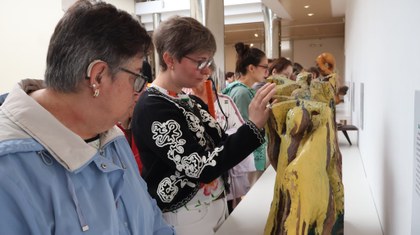 Una persona afiliada tocando una de las piezas de la exposición